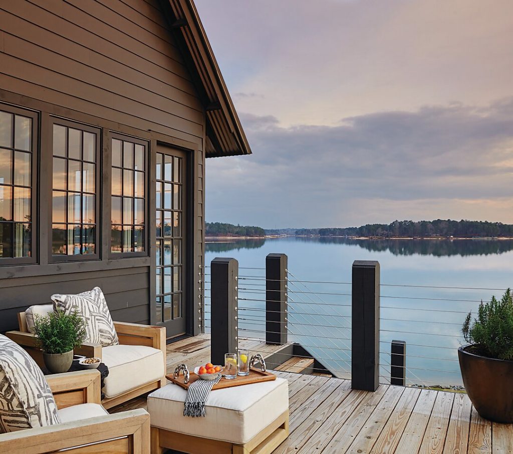 Lakeside deck with cream seating and a fire table at dusk