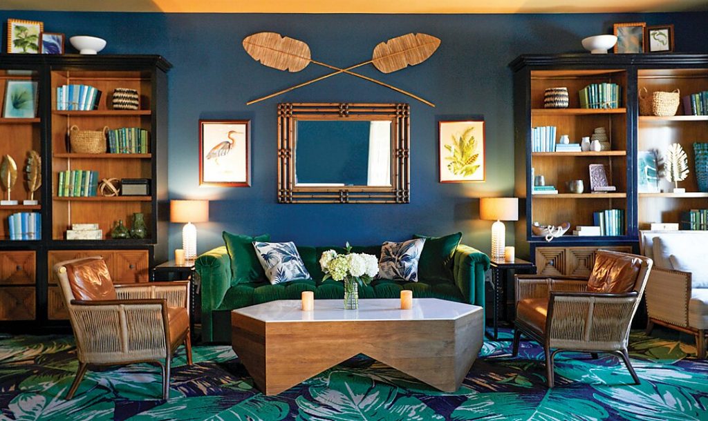 Navy library with built-in shelves, cane chairs and palm-print rug