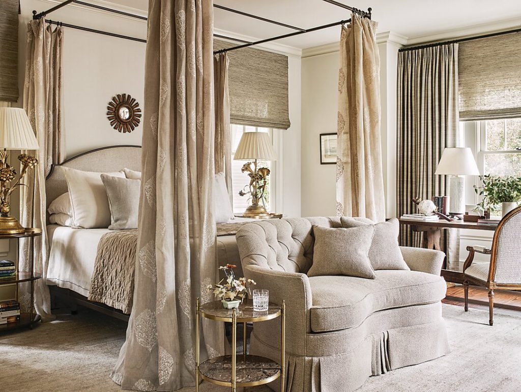 In the bedroom, an 18th-century English chest, mid-century bedside tables and lamps, antique Spanish library table, and Regency drinks table all live together harmoniously. In the wife’s bathroom, a glossy wallpaper imitates the look of lacquer. The mullioned windows over the tub add Craftsman charm to the space.