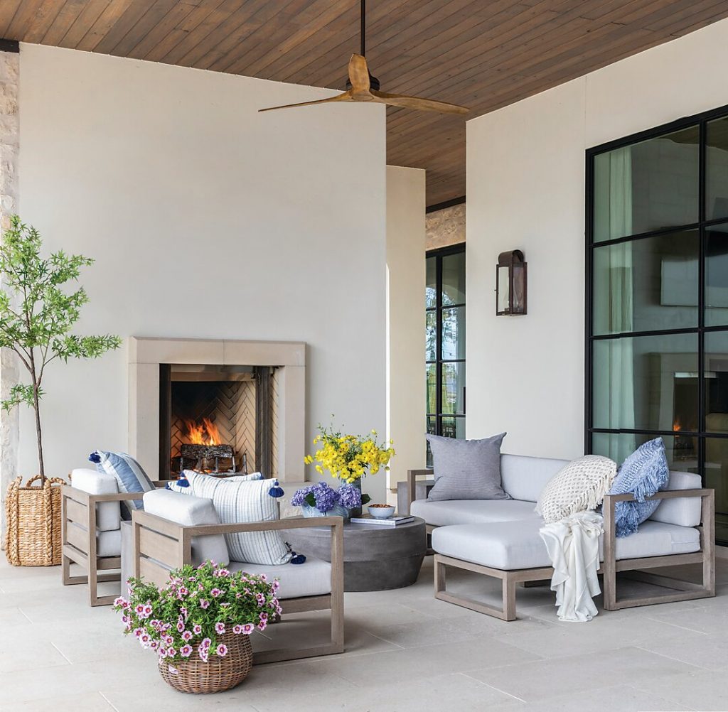 Porch sitting area with a fireplace, cream sofas and blue pillows