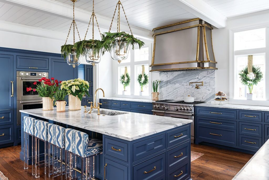 Navy kitchen with a marble island, brass hood and holiday wreaths