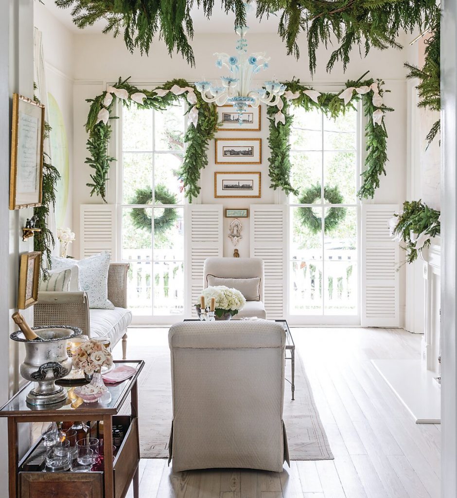 White room with wreaths and garland at the windows and a linen chair