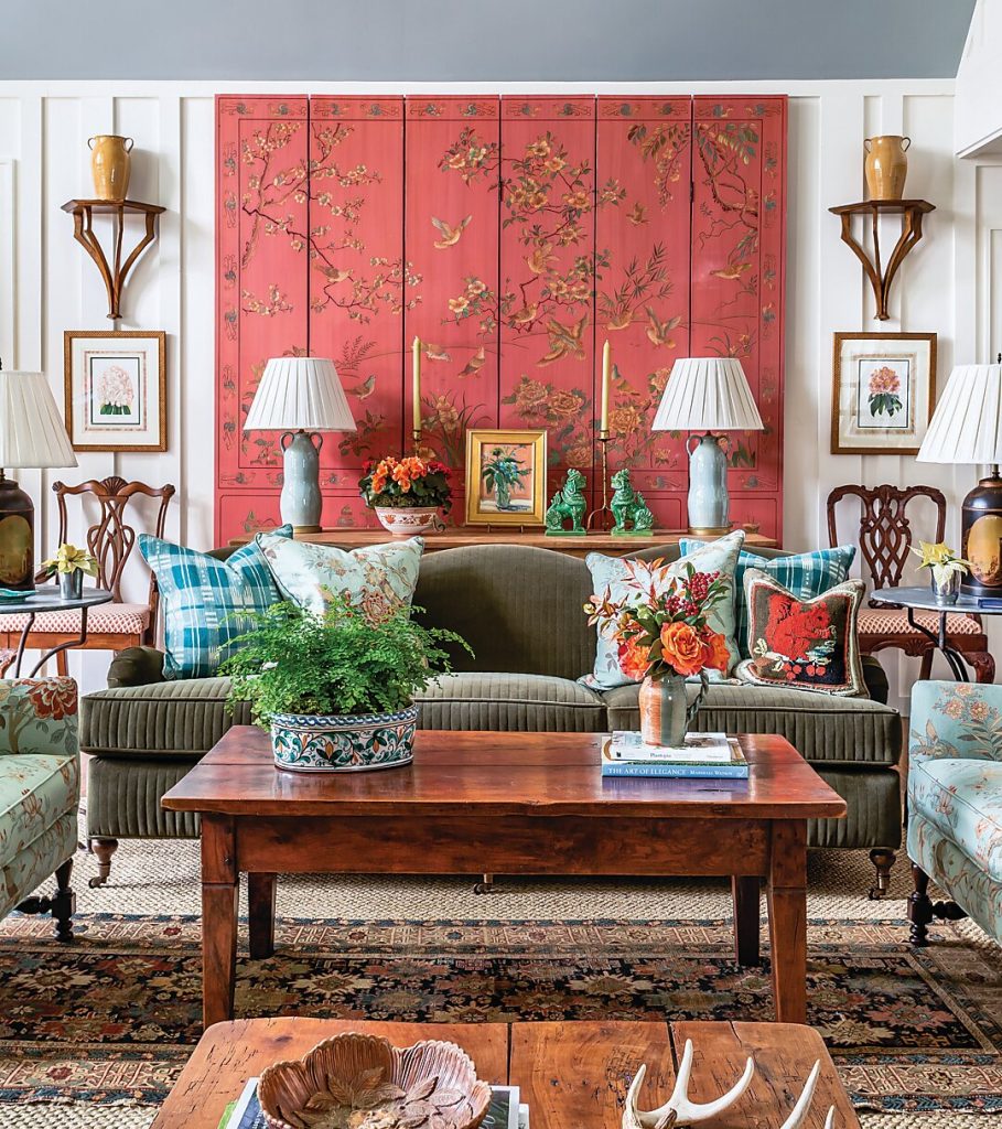 Sitting room with a coral chinoiserie panel, green sofa and framed prints
