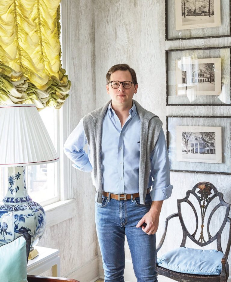 Man standing in a room with yellow curtains and framed prints