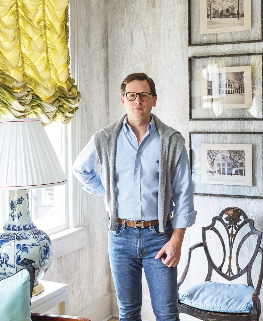 Man standing in a room with yellow curtains and framed prints