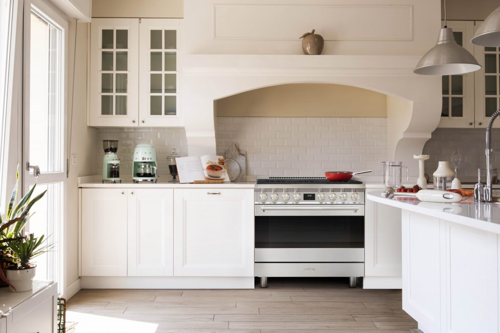 White kitchen with an arched plaster hood and a professional range
