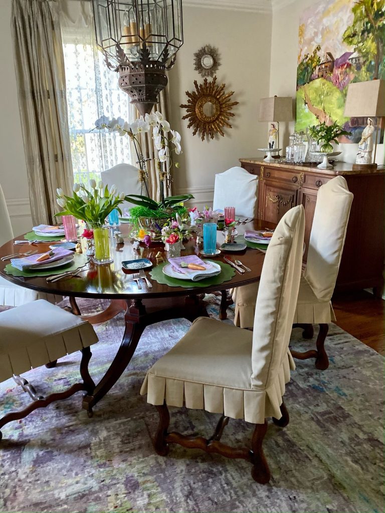 Dining table set with pastel china below an iron chandelier