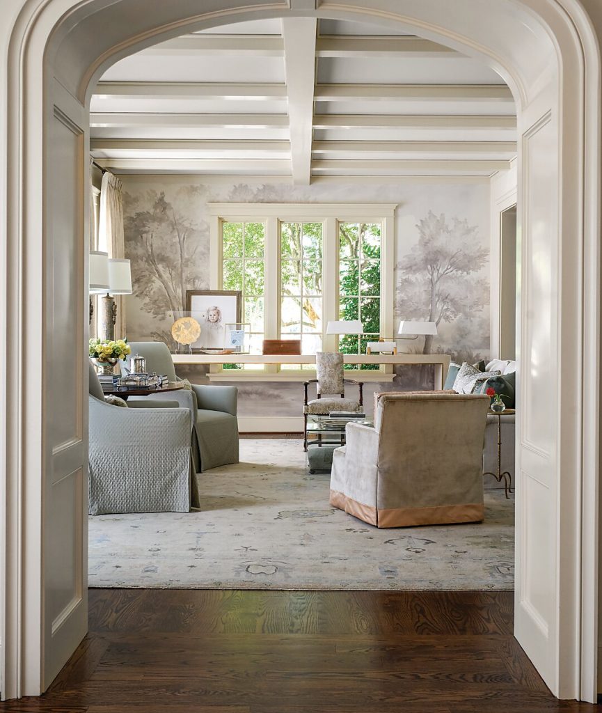 Arched opening looking into a pale living room under beams