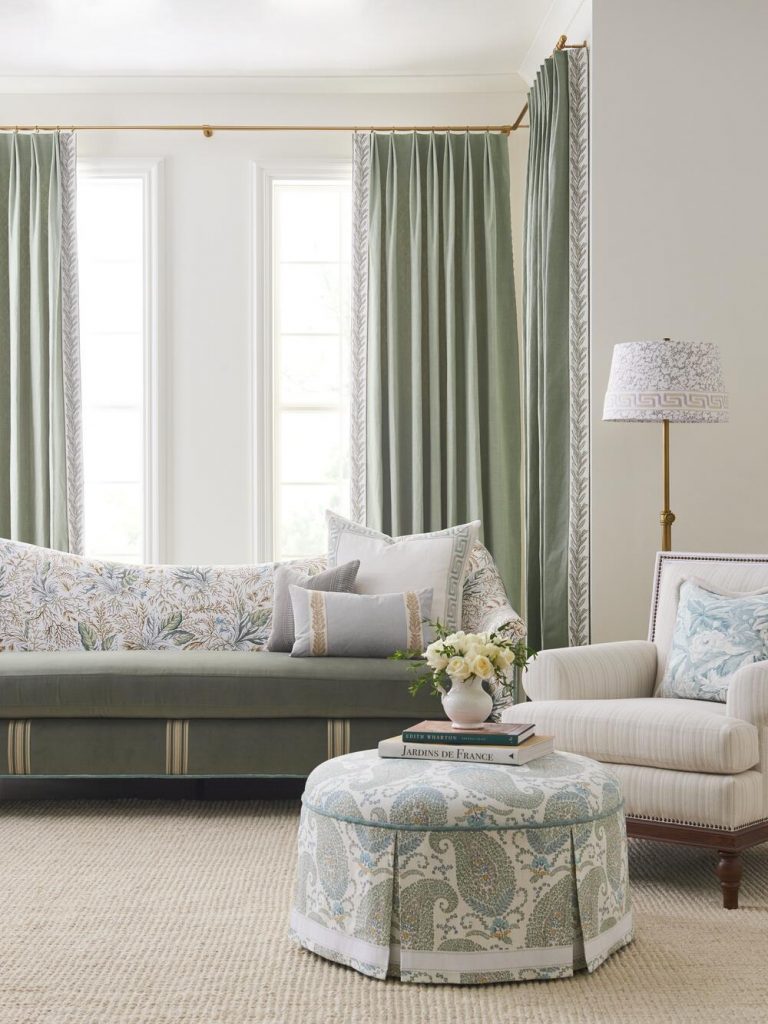 Bedroom with green curtains, a printed ottoman and a window bench