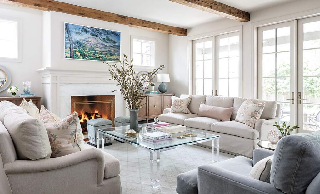 Living room with exposed beams, a stone mantel and grey slipcovered seating