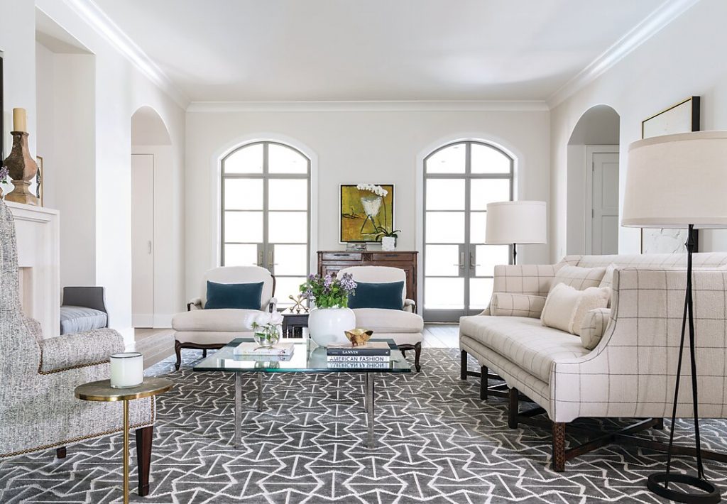 A silk-wool Shiir rug grounds the all-white living room. Its restrained palette and geometric design provide an edgy platform for elegant French antiques and traditional upholstered seating. Above: Stucco, limestone, copper, and slate give the new build Old World appeal and introduce interiors that brim with European antiques.