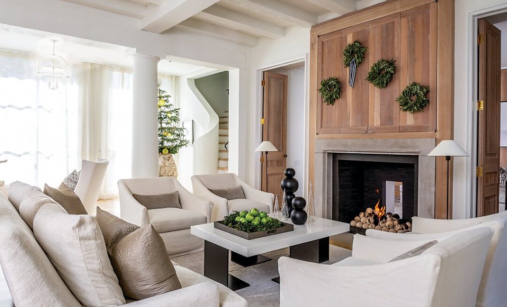 In the family room, a paneled fireplace surround conceals the television. Upholstered furniture surrounds a coffee table with a lacquered top designed by Liz Hand Woods. The fireplace opens to the study behind.