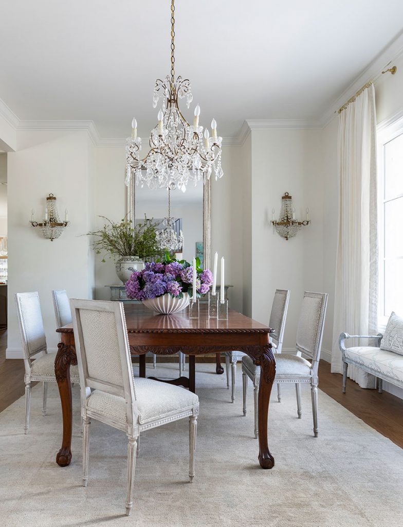 Dining room with a crystal chandelier, cream chairs and hydrangeas