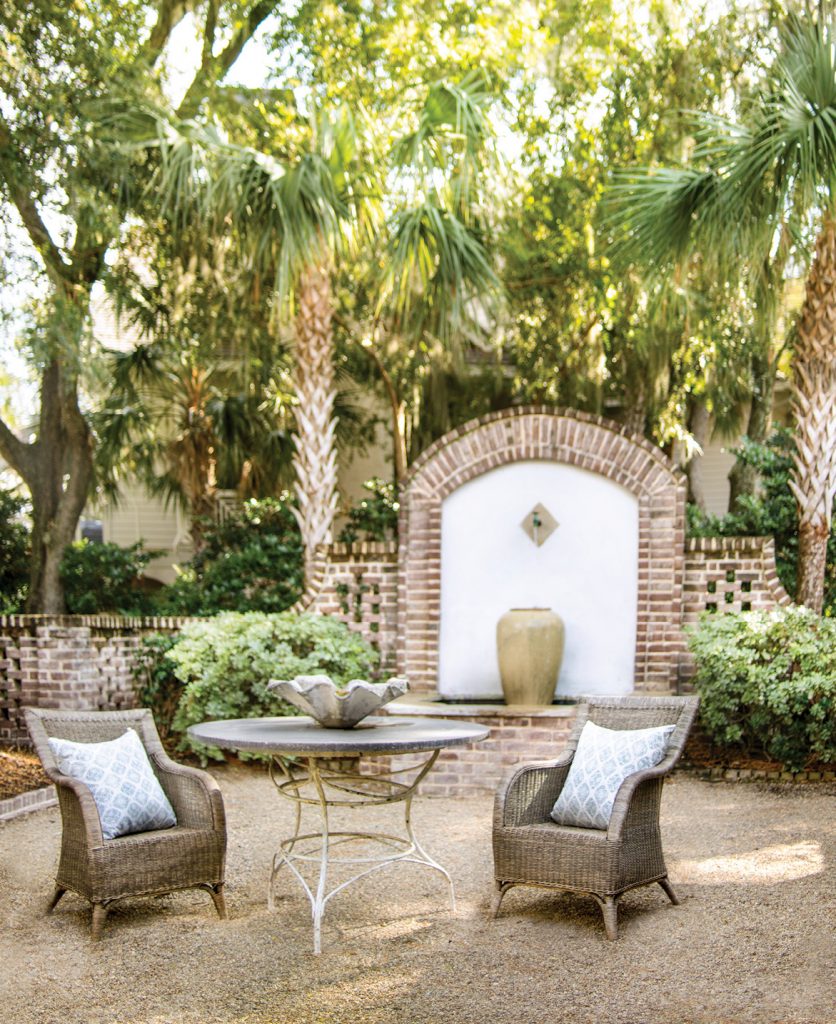 Courtyard with a stone wall fountain and woven armchairs
