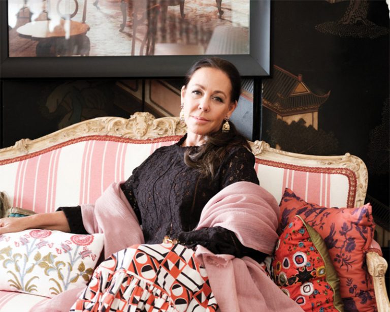 Woman in pink seated on a striped settee before a chinoiserie panel