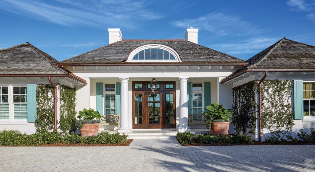 Low white house with a fanlight entry and clipped plantings
