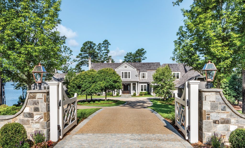 Stone gate piers and a gravel drive leading to a white house
