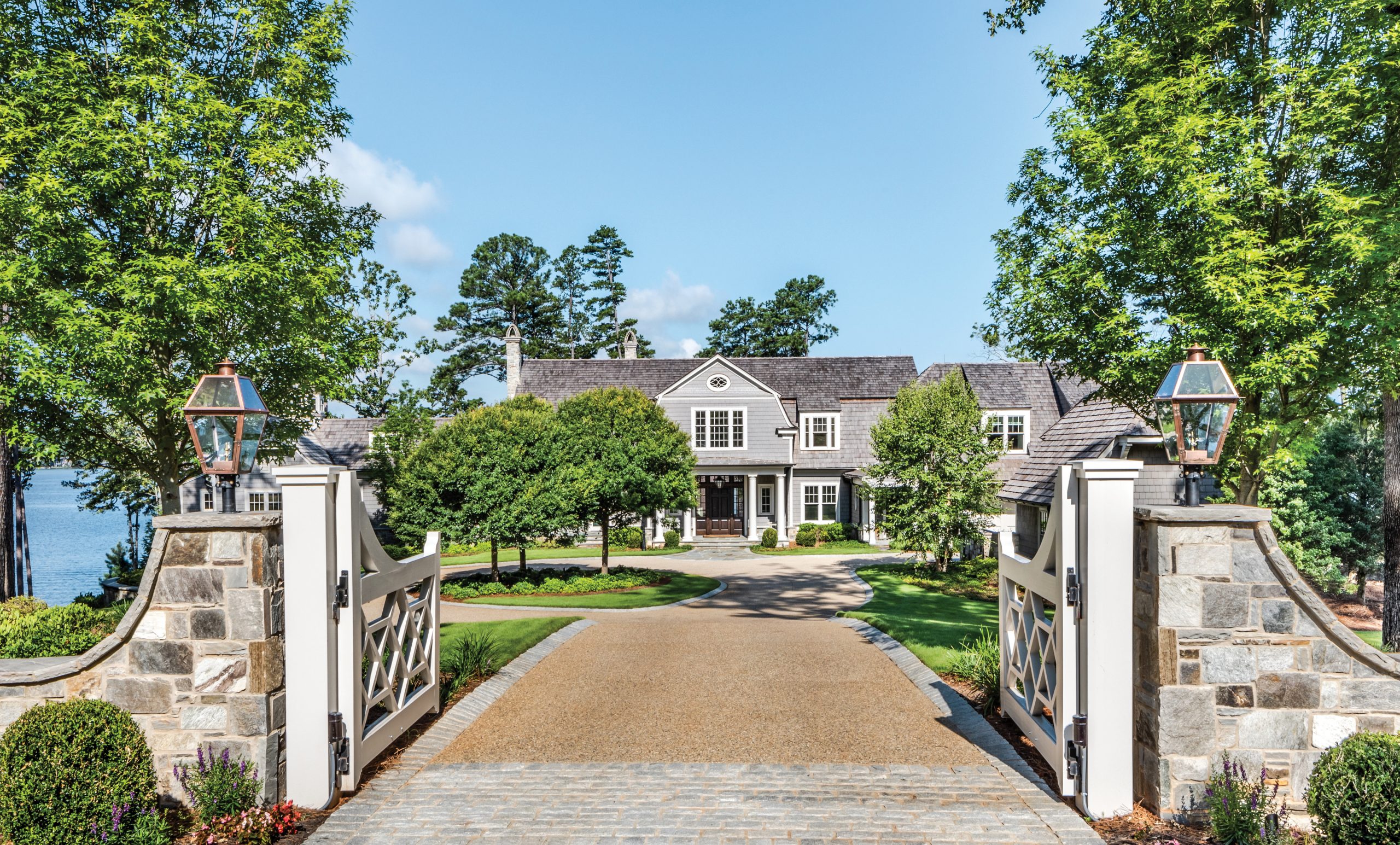Stone gate piers and a gravel drive leading to a white house