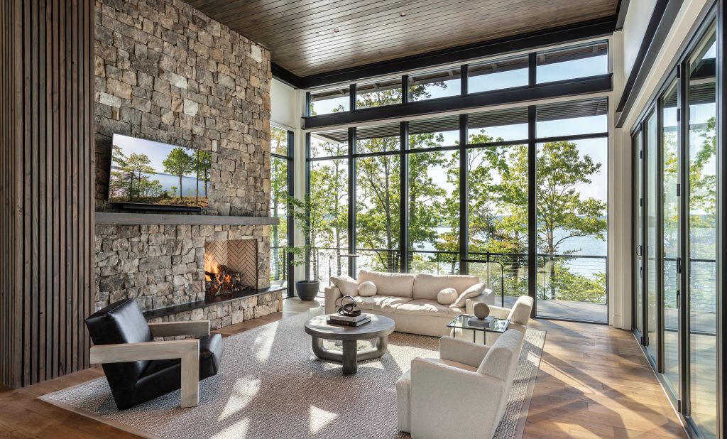 Living room with a stone fireplace, dark wood ceiling and lake views