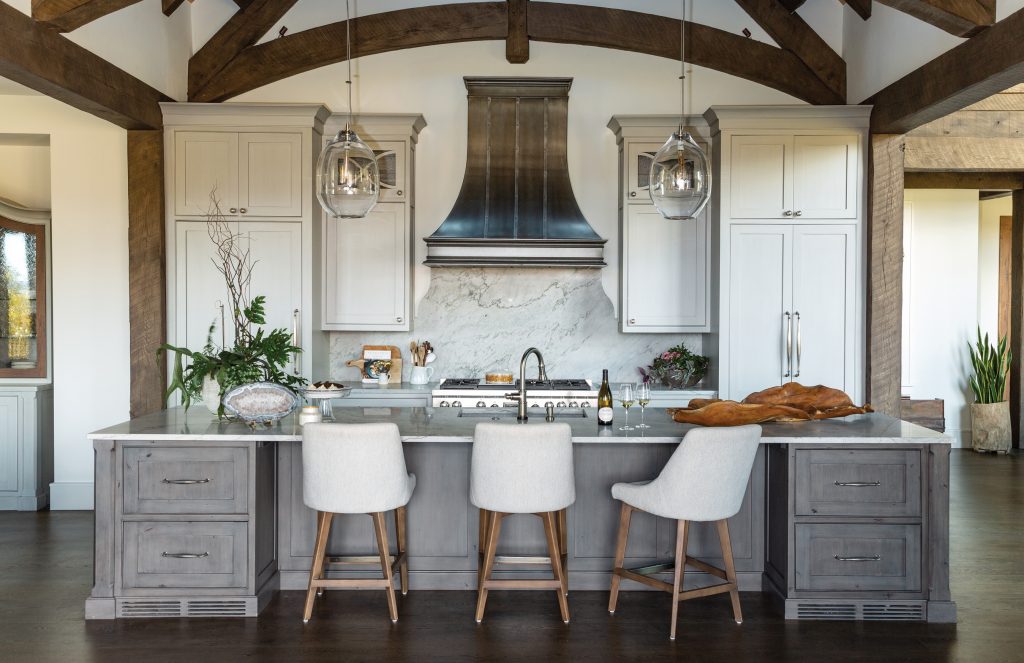Kitchen with a zinc hood, timber trusses and white counter stools