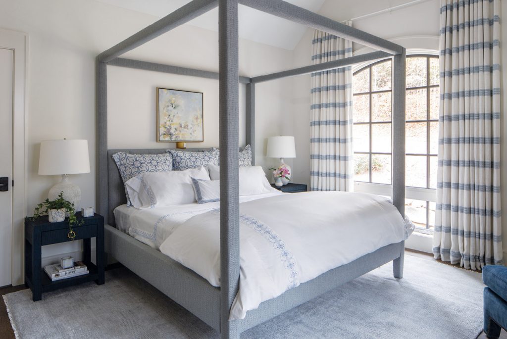 Bedroom with a grey canopy bed and buffalo check curtains