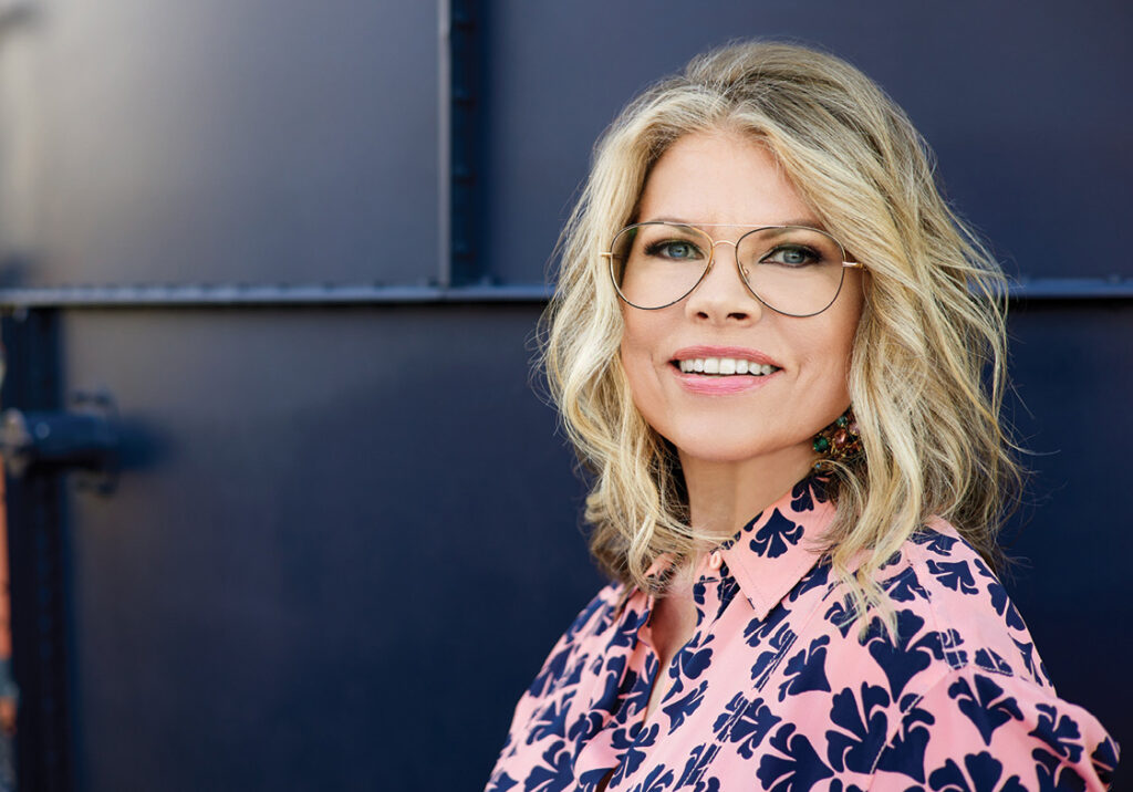 Portrait of a woman in a pink printed blouse against a navy door