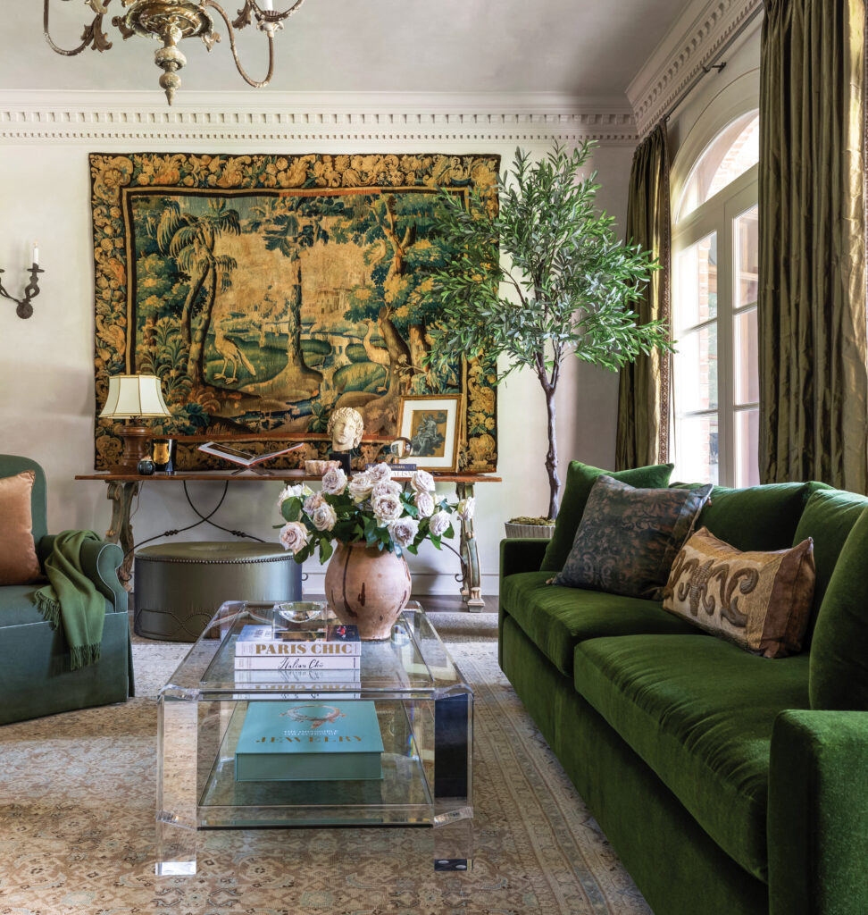 Living room with a tapestry, green velvet sofas and a lucite table