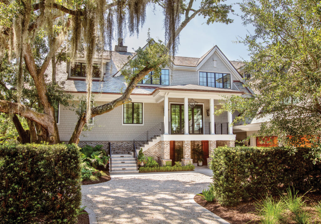 Shingled house with porches framed by mossy live oaks