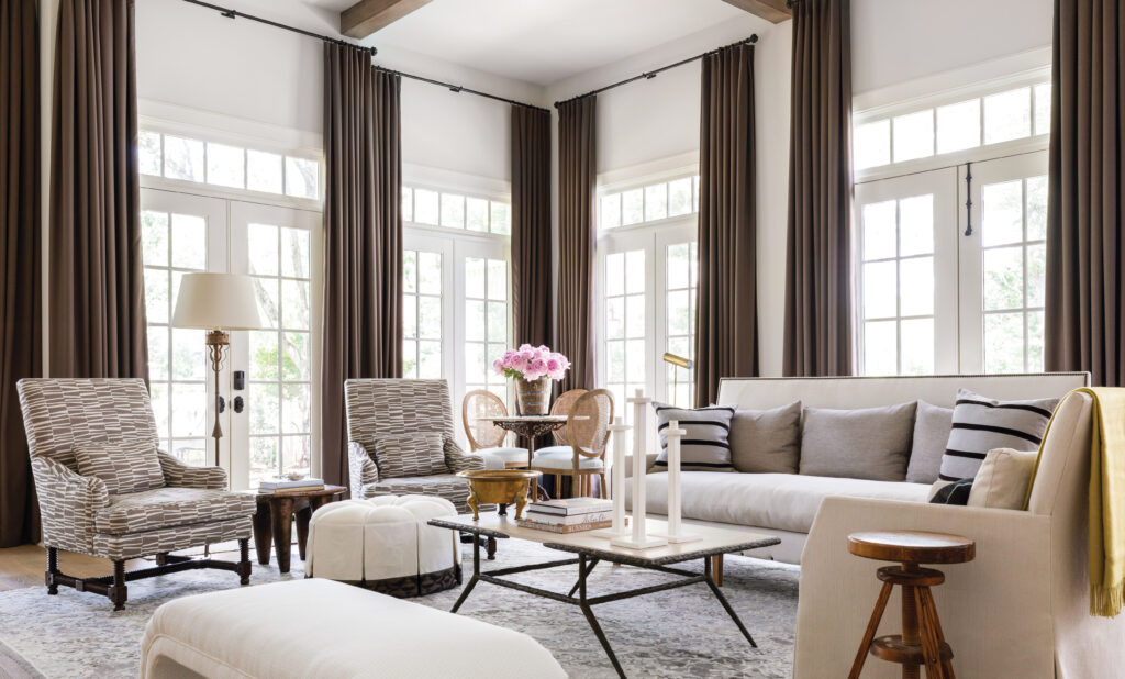 Living room with tall grey curtains, wing chairs and a round table