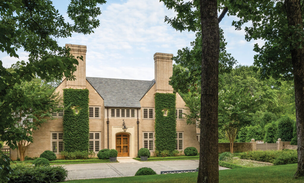 Ivy-covered stone house behind a lawn and mature trees