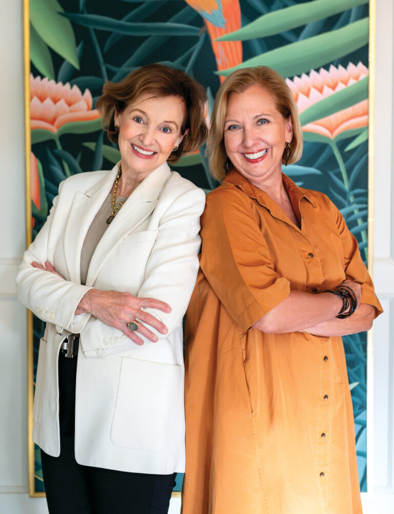 Two women standing in front of a brightly painted mural