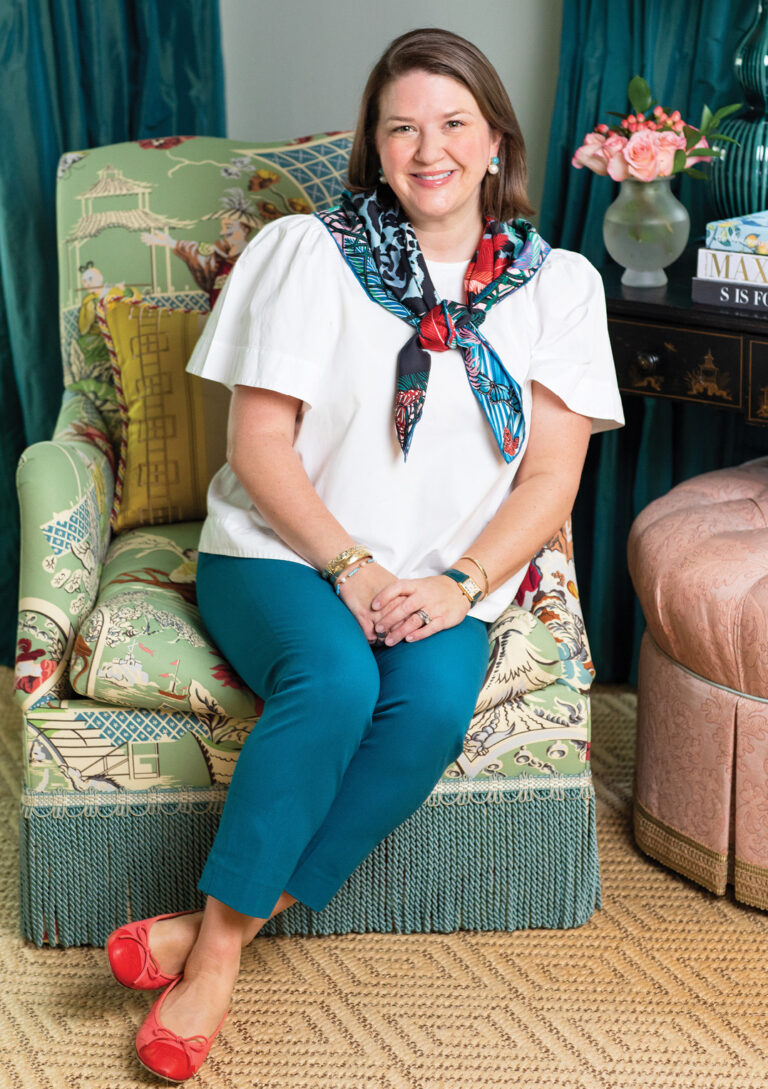 Woman seated in a green striped armchair before teal curtains