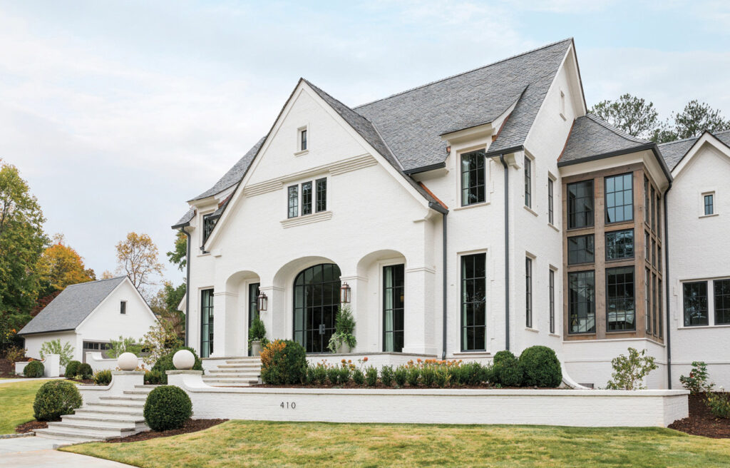 White house with steep gables and black windows on a green lawn