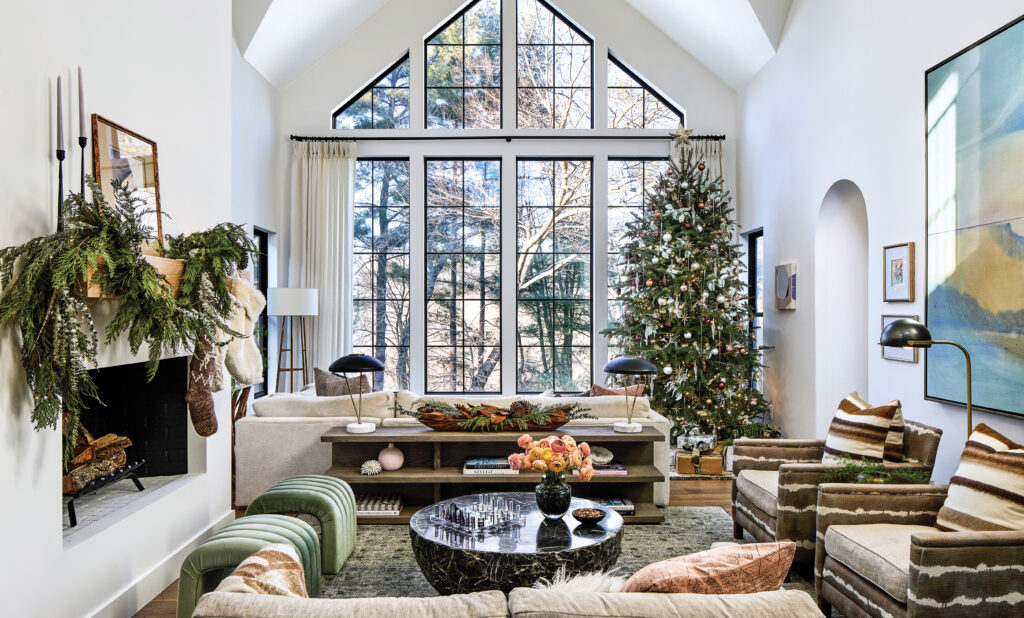 Two-story living room with a garlanded mantel, tree and green chairs