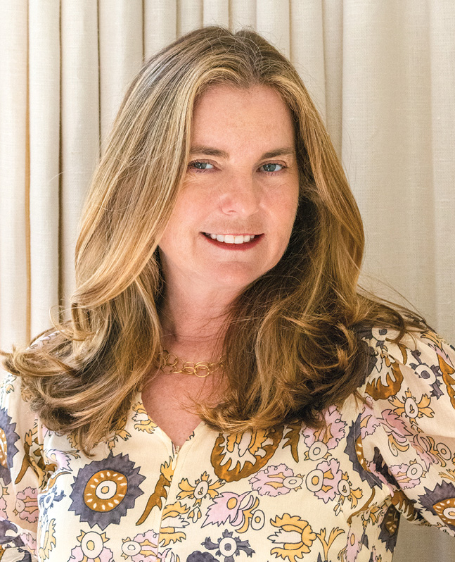 Portrait of a woman in a patterned blouse against a pale column