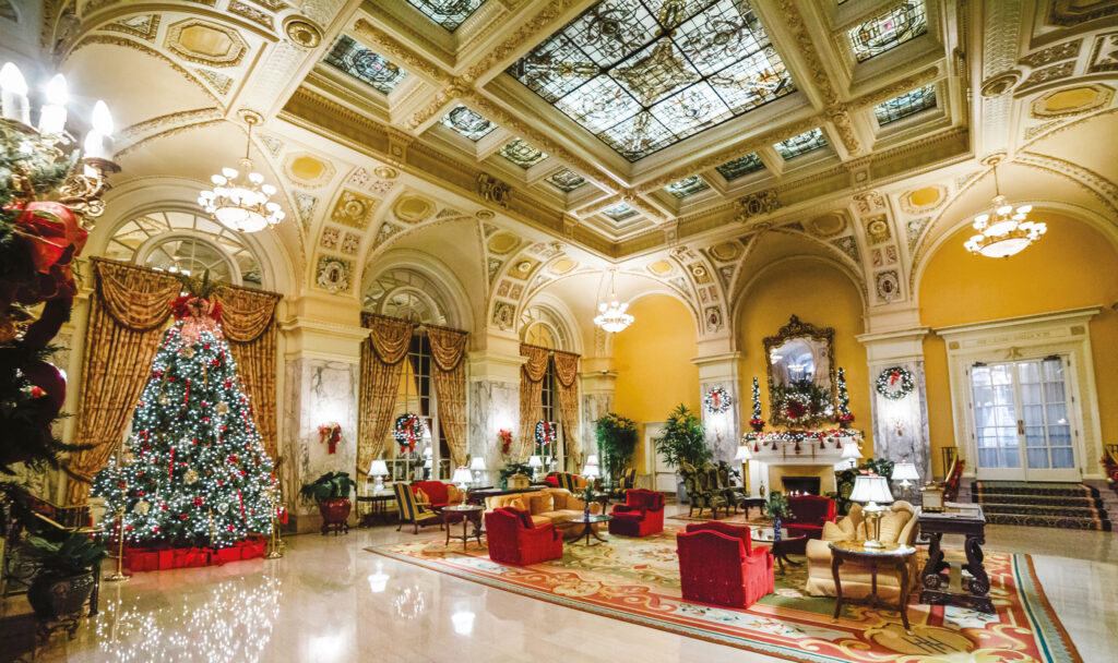 Gilded hotel lobby with a decorated tree and stained-glass ceiling