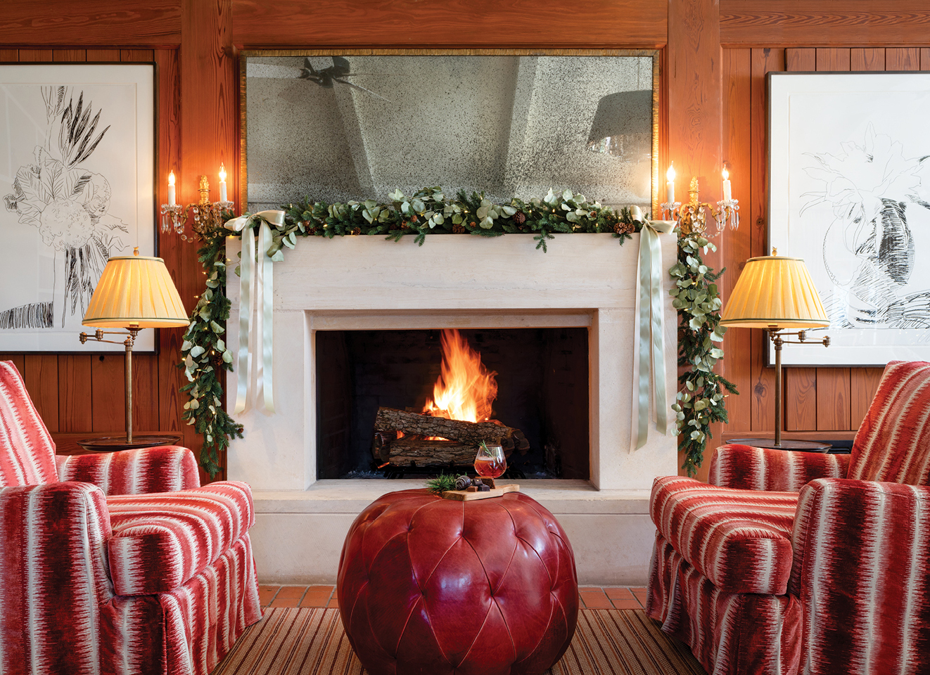 Panelled room with a garlanded mantel, lit fire and striped chairs