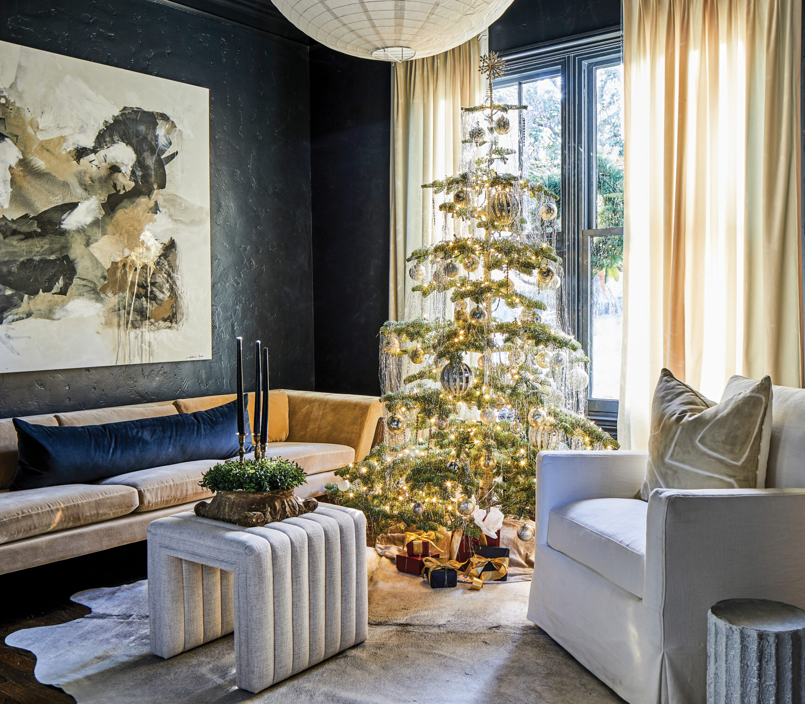 Navy sitting room with a decorated tree and cream chairs