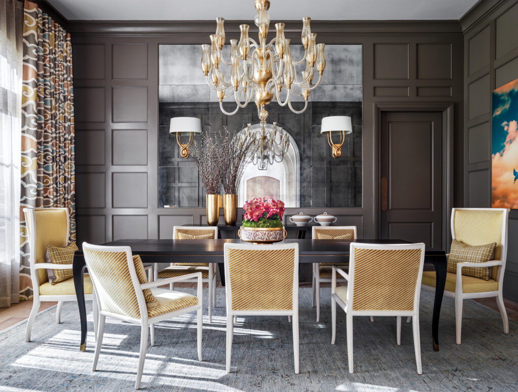 Dining room with grey panelling, a crystal chandelier and gold chairs