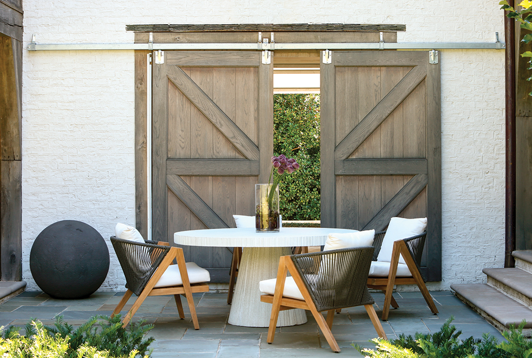 Courtyard table with white chairs before weathered barn doors