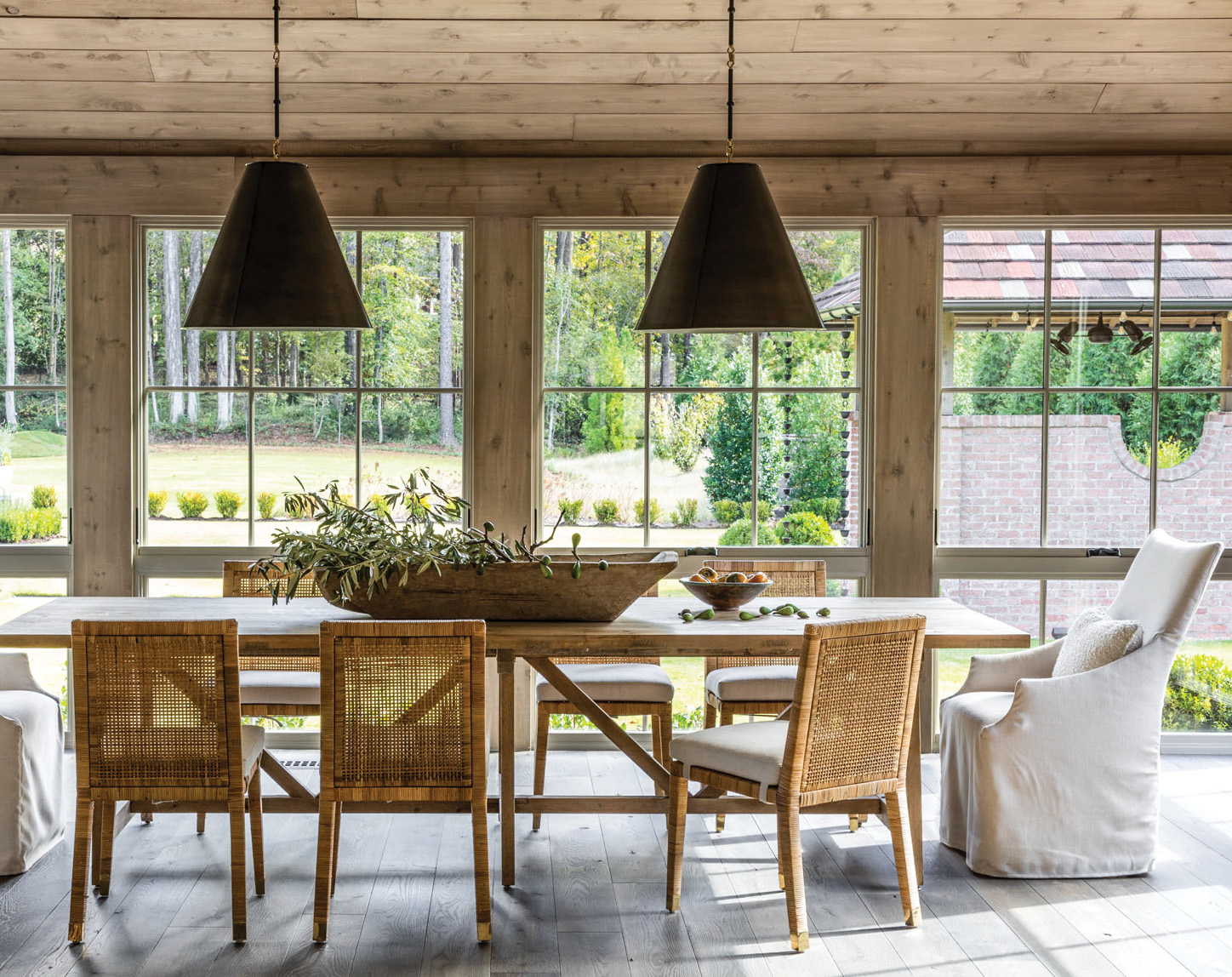 Dining table with rattan chairs below black cone pendants