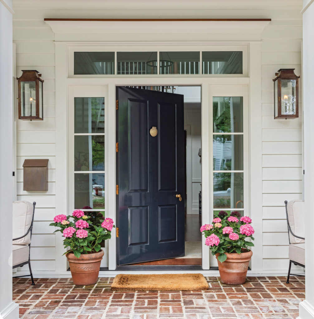 Navy front door with sidelights and pink flowers in urns