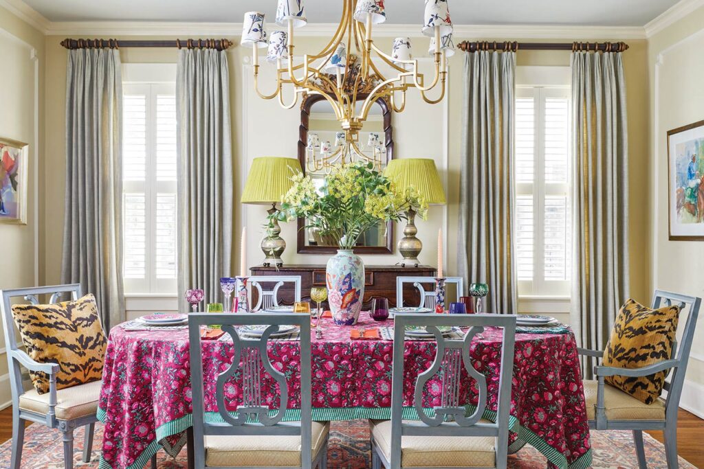 Dining room with yellow lamps, a pink cloth and patterned chairs