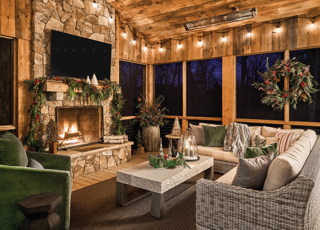 Screened porch with a stone fireplace, wicker chairs and festoon lights