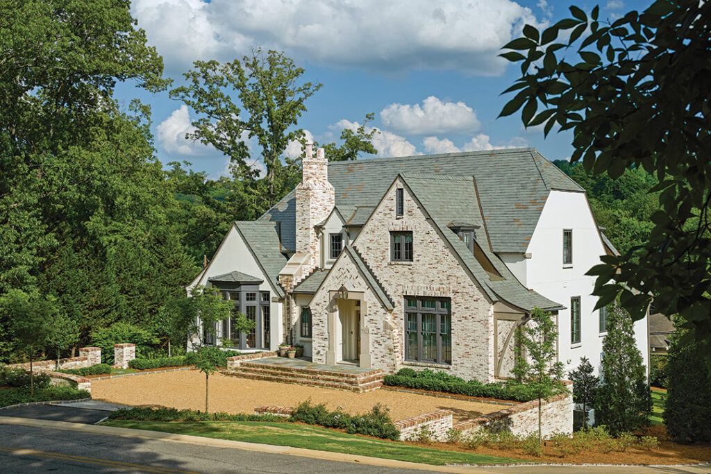 Stone and white house with steep gables behind a lawn