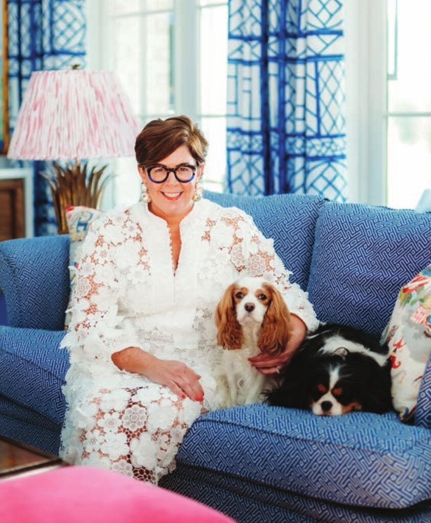 Woman in a floral blouse on a blue sofa with a spaniel