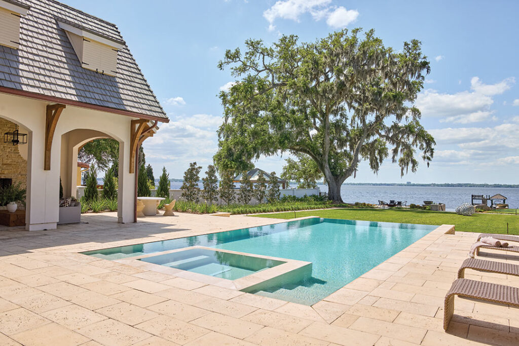Pool with loungers beside a stone arch and a bay view