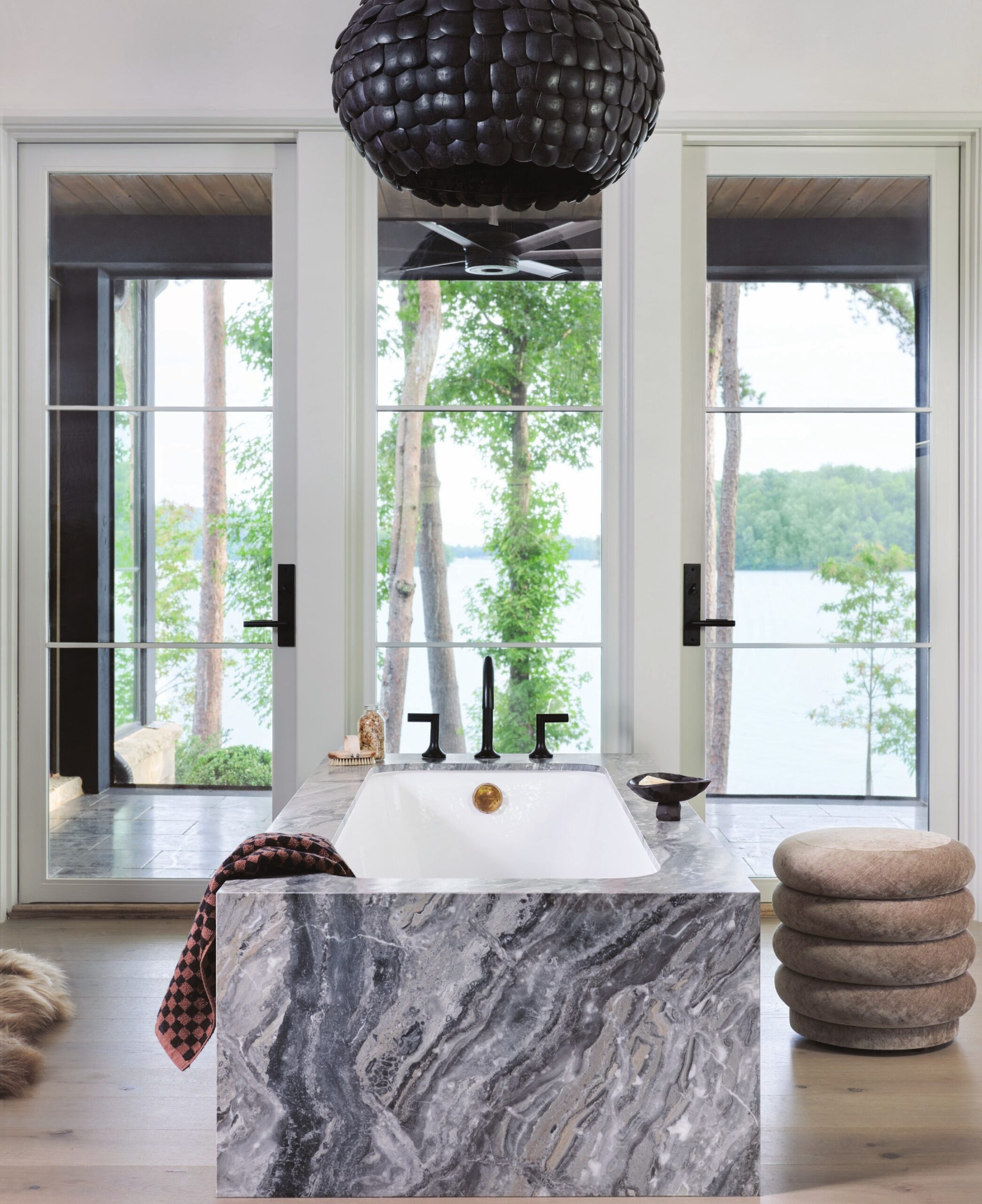 Arguably the best seat in the house, the primary bathroom’s Waterworks soaking tub is perfectly positioned to take in Lake Keowee. A luminous, textured black lighting fixture from Arteriors crowns the space.