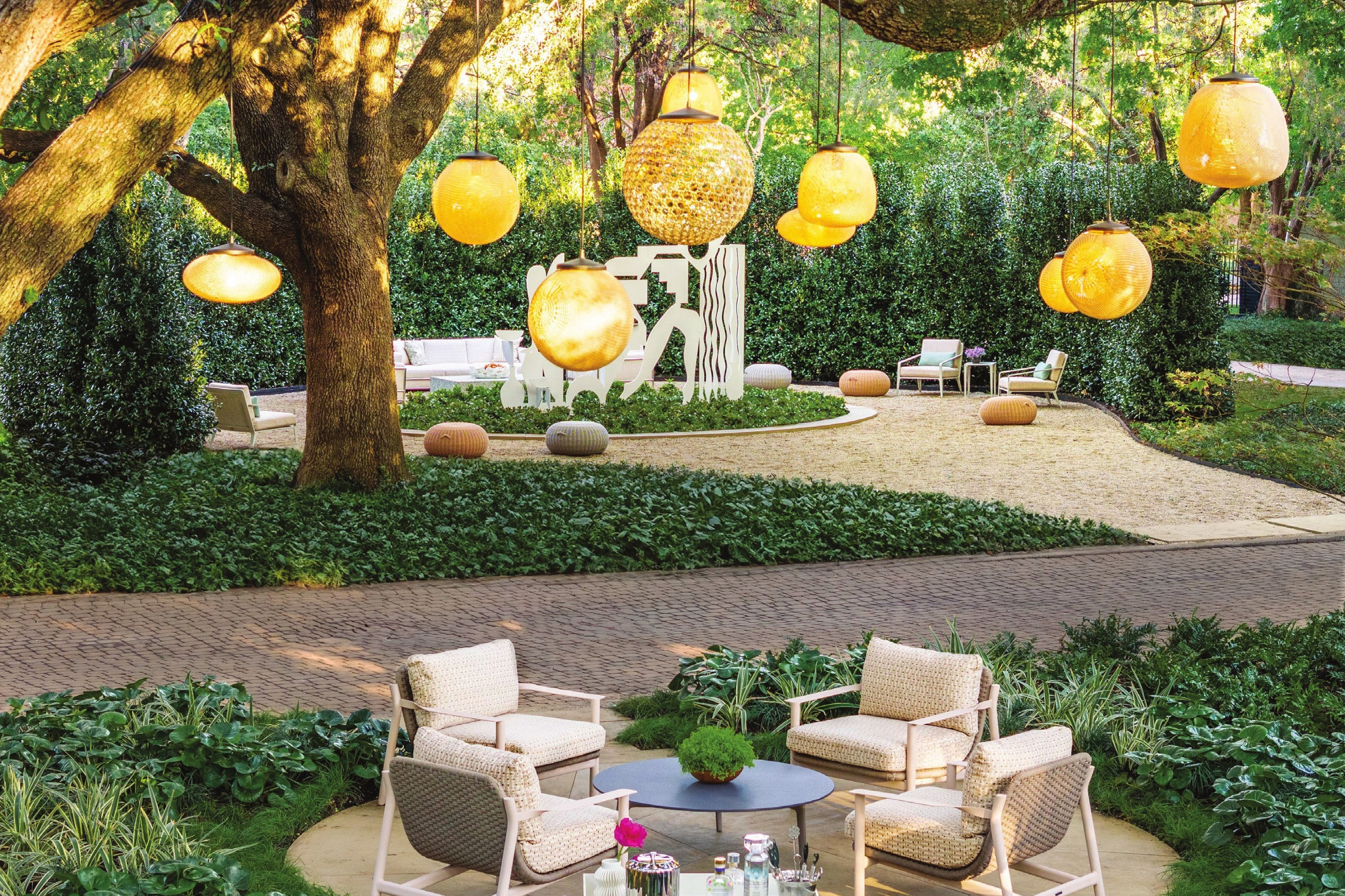 Garden seating under a live oak hung with round lanterns