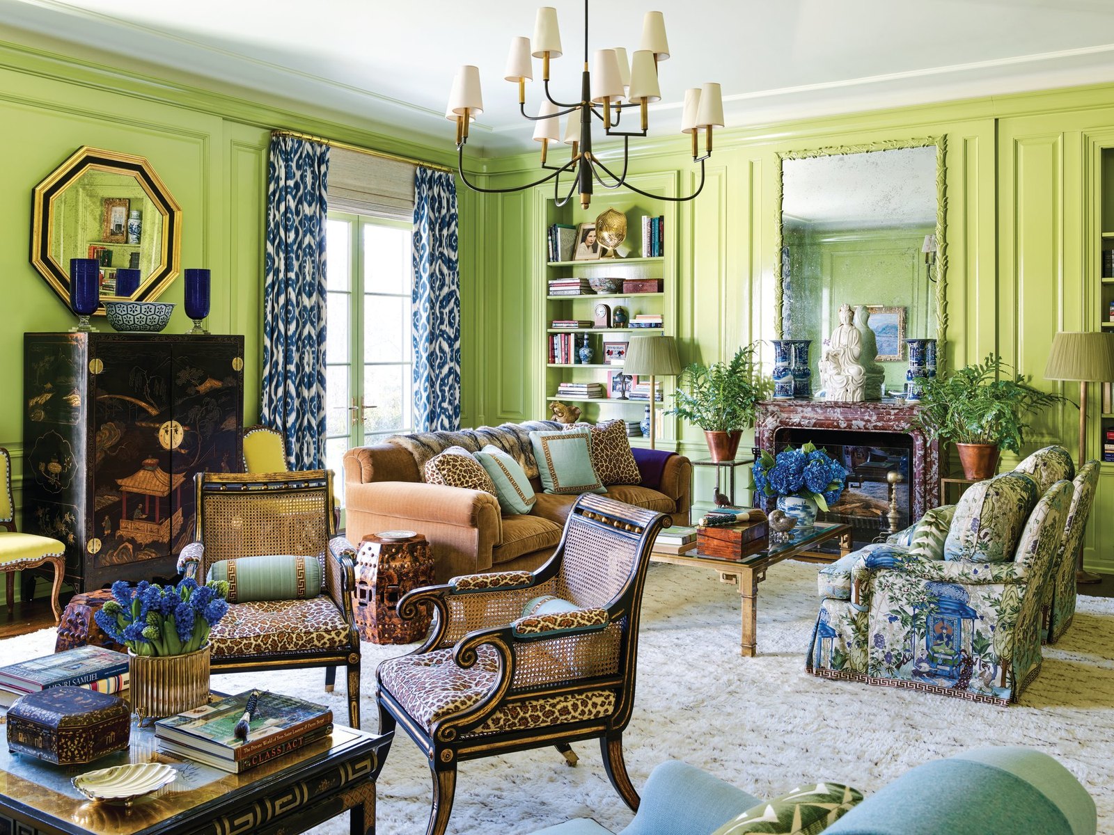 Chartreuse lacquered library with a blue-and-white ikat curtain, chinoiserie cabinet, leopard-print seating, and a marble mantel